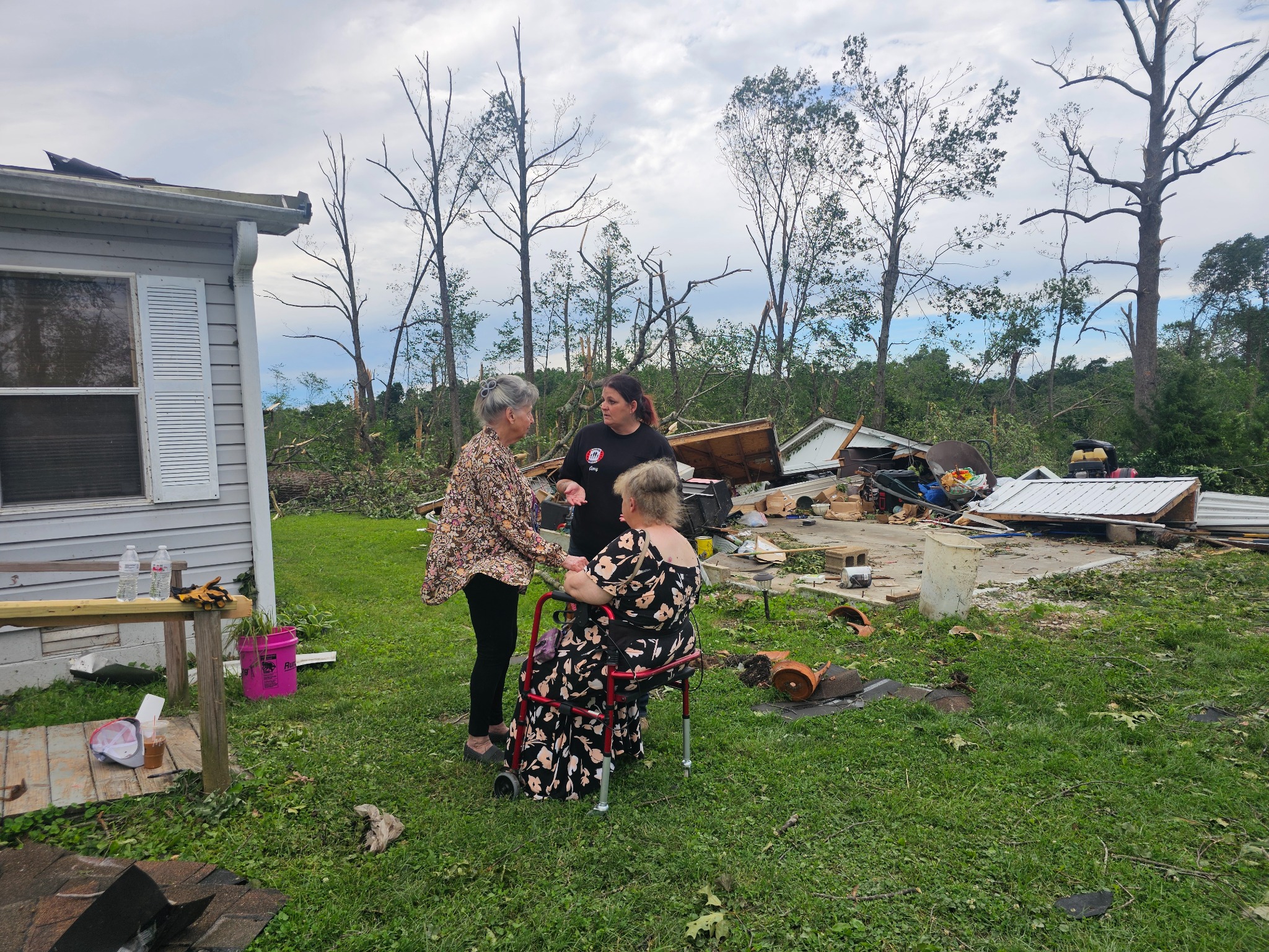 An American Regulators USA responder listening to two residents outside a storm-damaged home