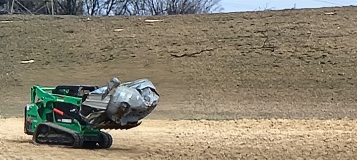 A tracked loader clears a tornado-damaged field in Springfield, Ohio