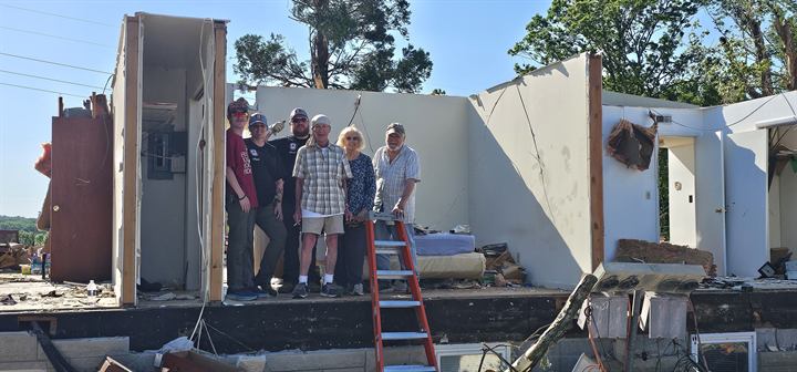 Team members stand in the remains of a tornado-destroyed home